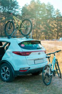Kia Sportage with mountain bikes in scenic forest, ideal for adventure travel.