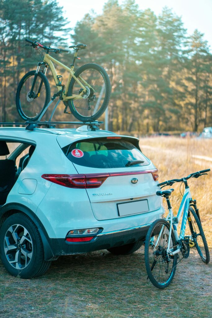 Kia Sportage with mountain bikes in scenic forest, ideal for adventure travel.