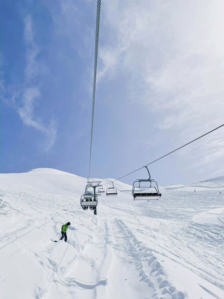 A skier conquers a snow-covered mountain under clear blue skies and ski lifts.