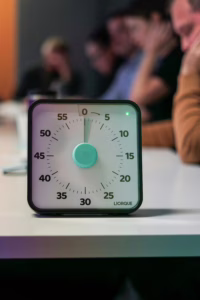 Close-up of a timer in focus during a busy office meeting.